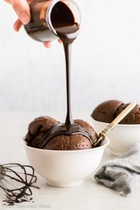 icecream in a bowl topped with chocolate syrup being poured